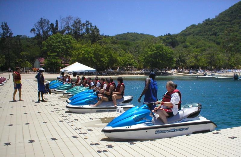 White modular floating pontoon platform at beach resort, people preparing jet skis for water activities