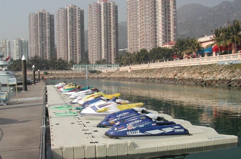 Rotomolded HDPE floating pontoon dock with jet skis parked at coastal marina, modular plastic floating dock for watercraft mooring
